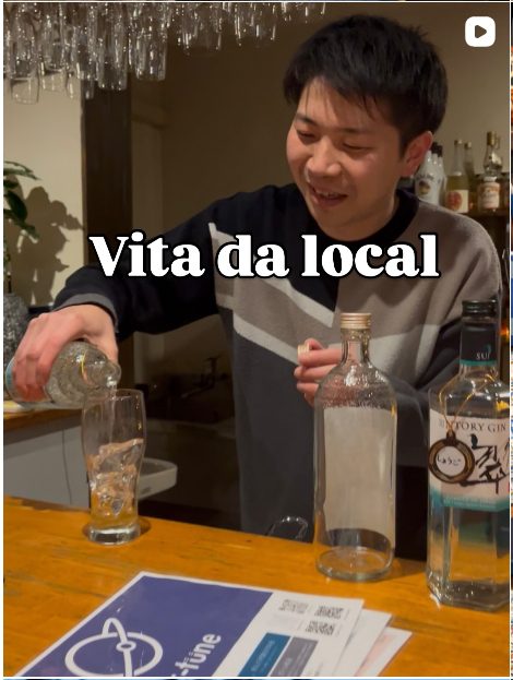 Foto di copertina dal feed Instagram con un ragazzo giapponese che serve sake da dietro il bancone e la scritta "Vita da local"