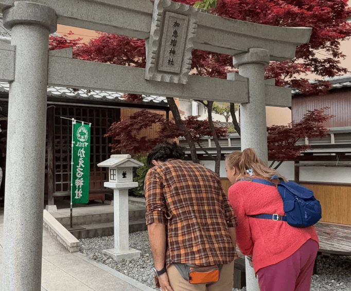 Emy e Morris di spalle che si inchinano di fronte al torii del Kaeru Jinja, santuario di Gero Onsen